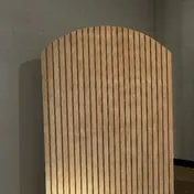The wood slat arch backdrop on its own against a wall