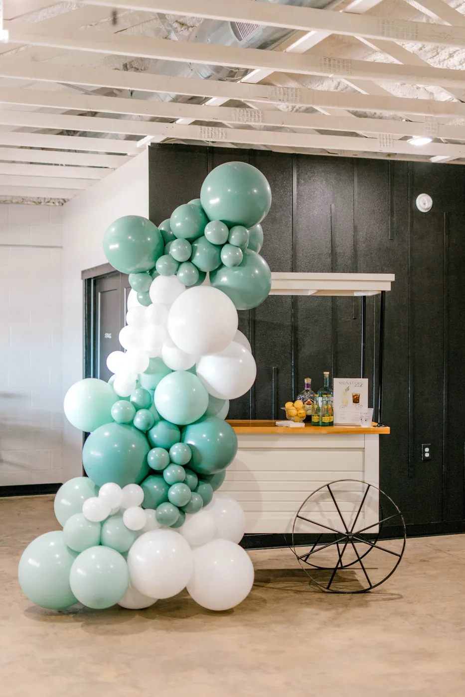 Sage and white balloon garland over the bar cart
