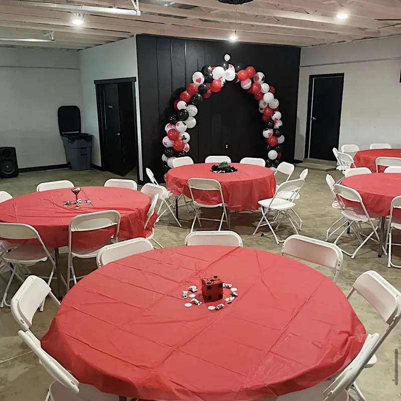 Red tables under a red, black and white balloon arch for a casino night
