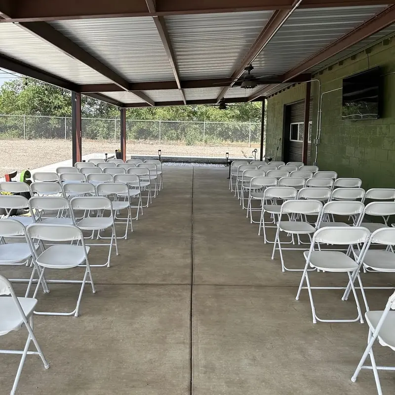 Rows of white chairs set for a ceremony on the covered patio