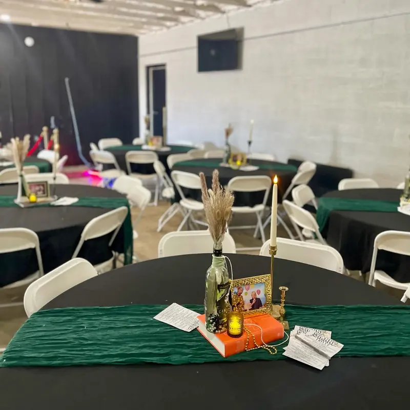 Black linens with green runners, candles and photos on each table