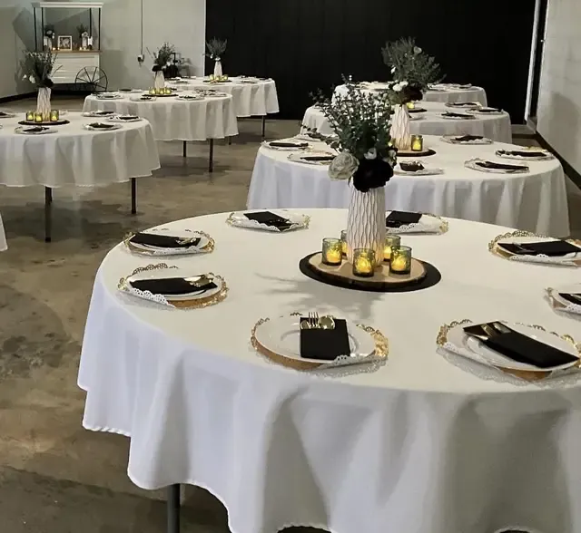 White linens with gold chargers and greenery