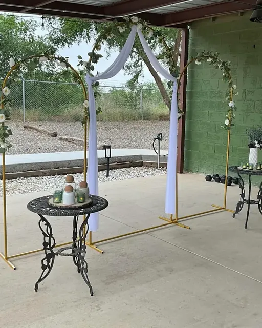 A gold arch with white drapes on the patio
