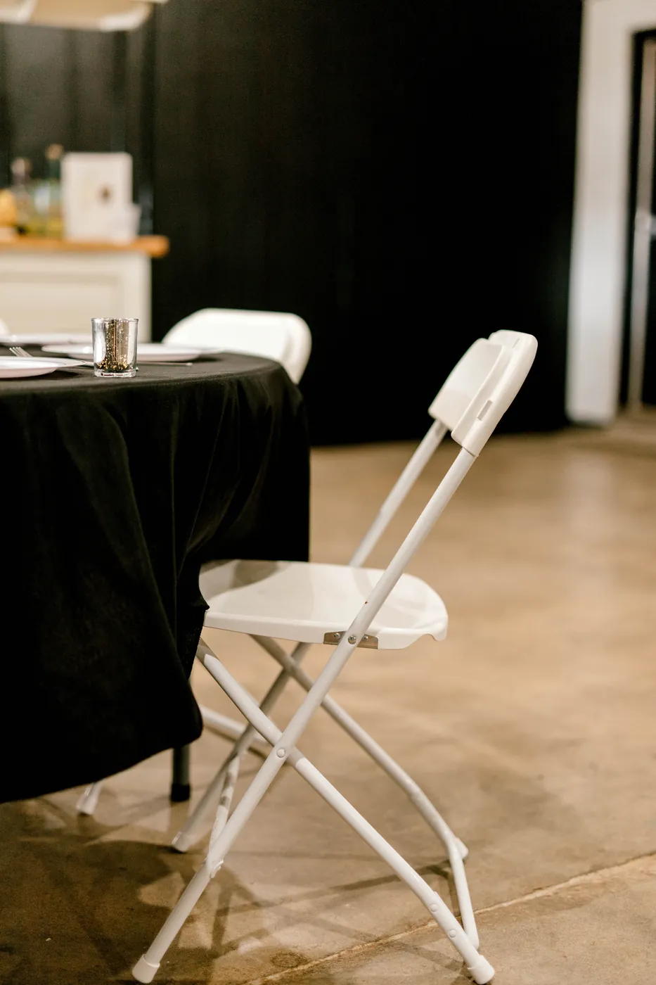 A white chair pulled up to a black-linen table